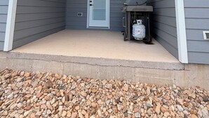 Un espace extérieur abrité, doté d’une porte, d’un barbecue et d’une bouteille de propane.