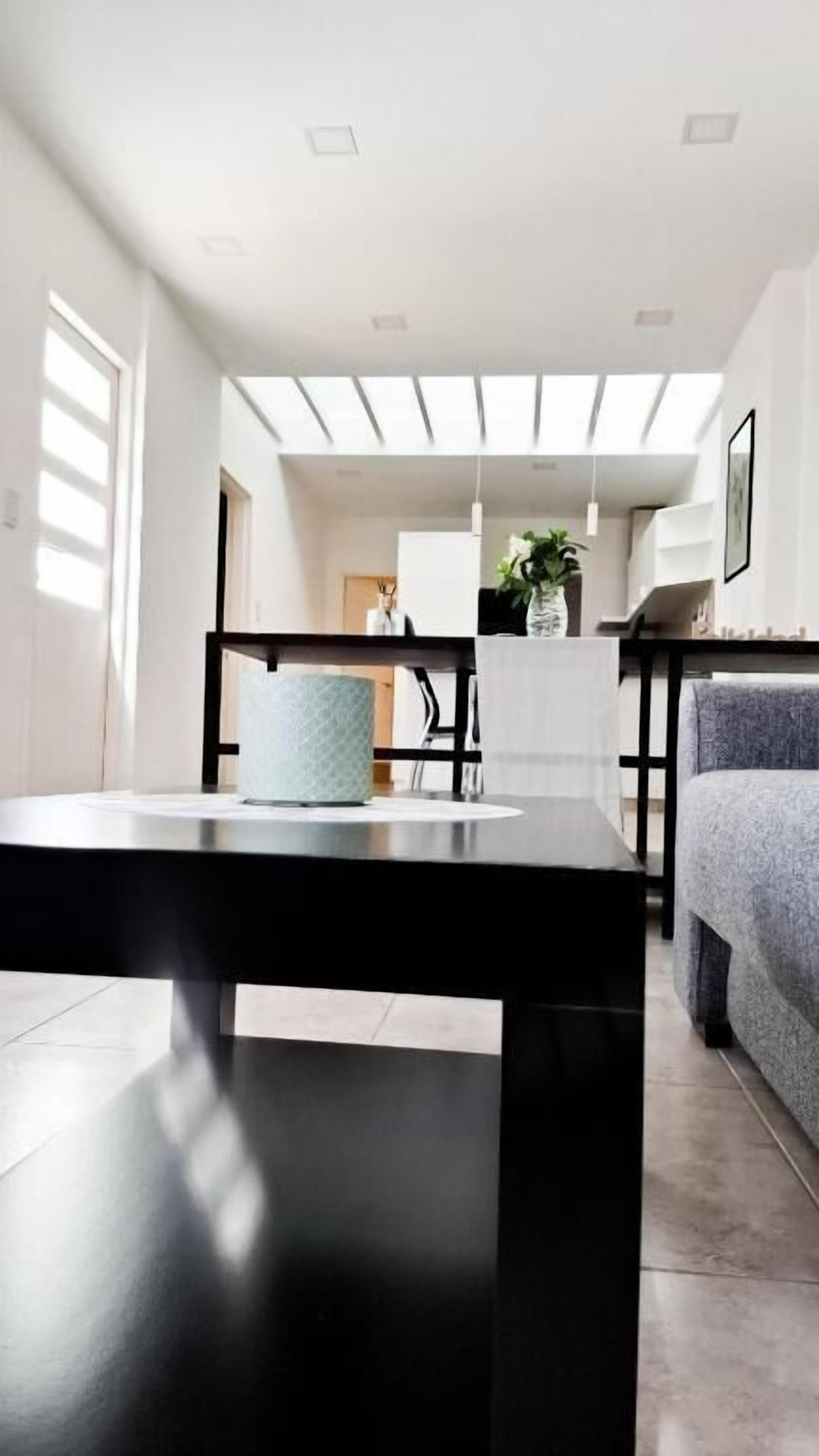 A modern living room with a black table, a grey sofa, and a white armchair.