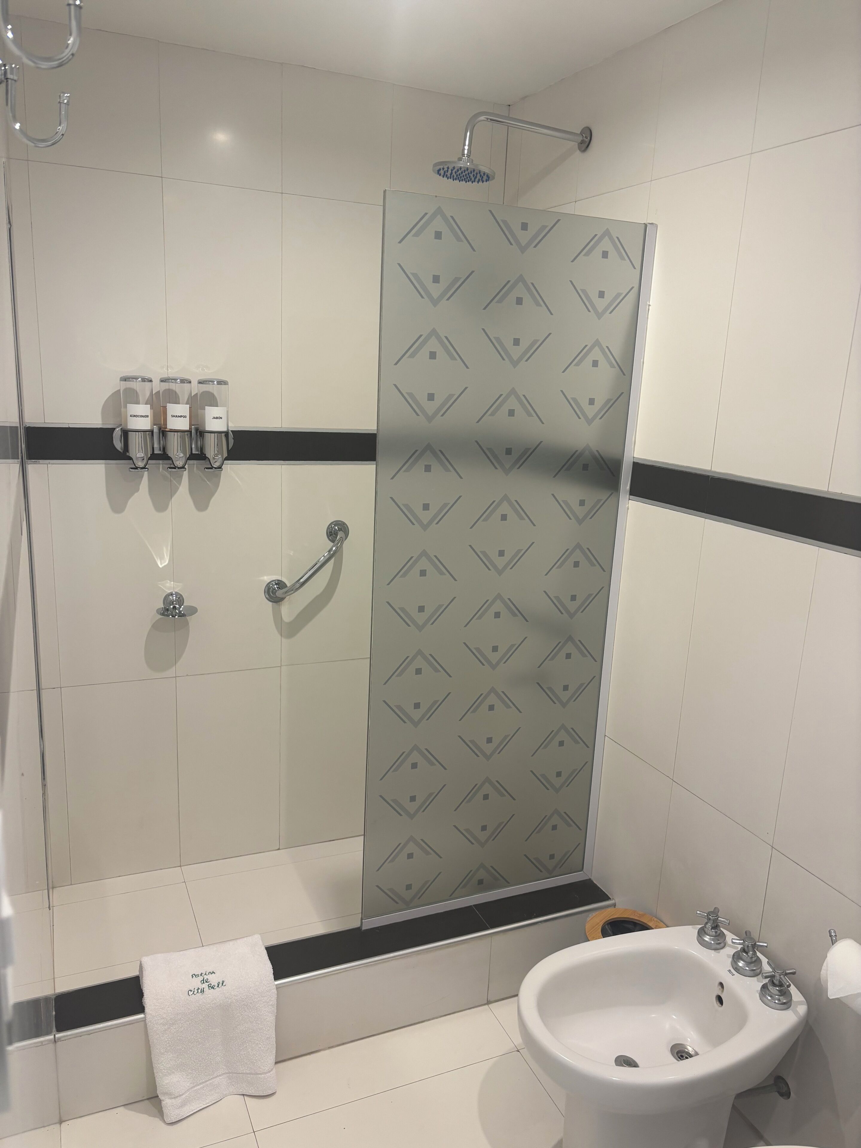 A bathroom with a shower, a sink, and a towel rack with bottles.