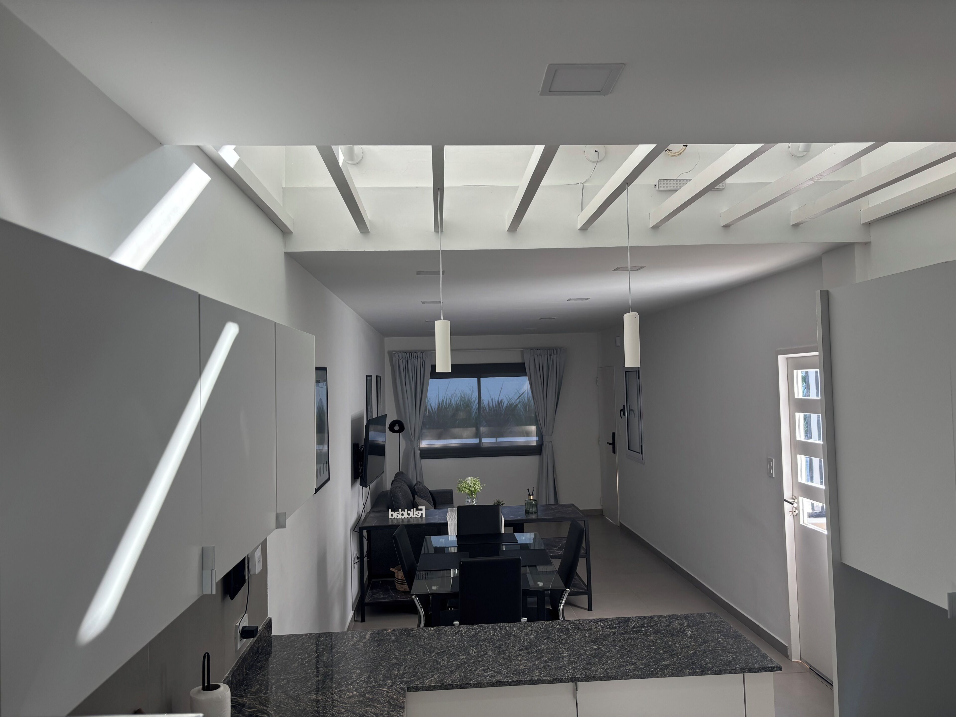 A modern interior with a dining area, kitchen, and a view of the outdoors.