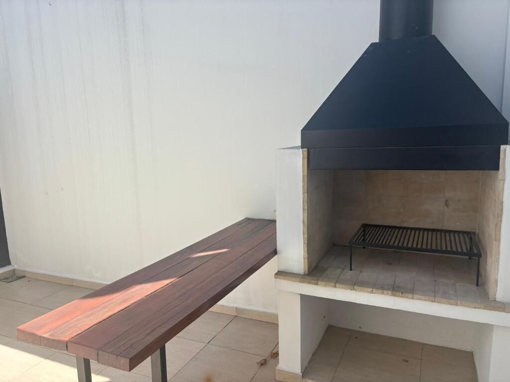 A barbecue grill with a bench in front.