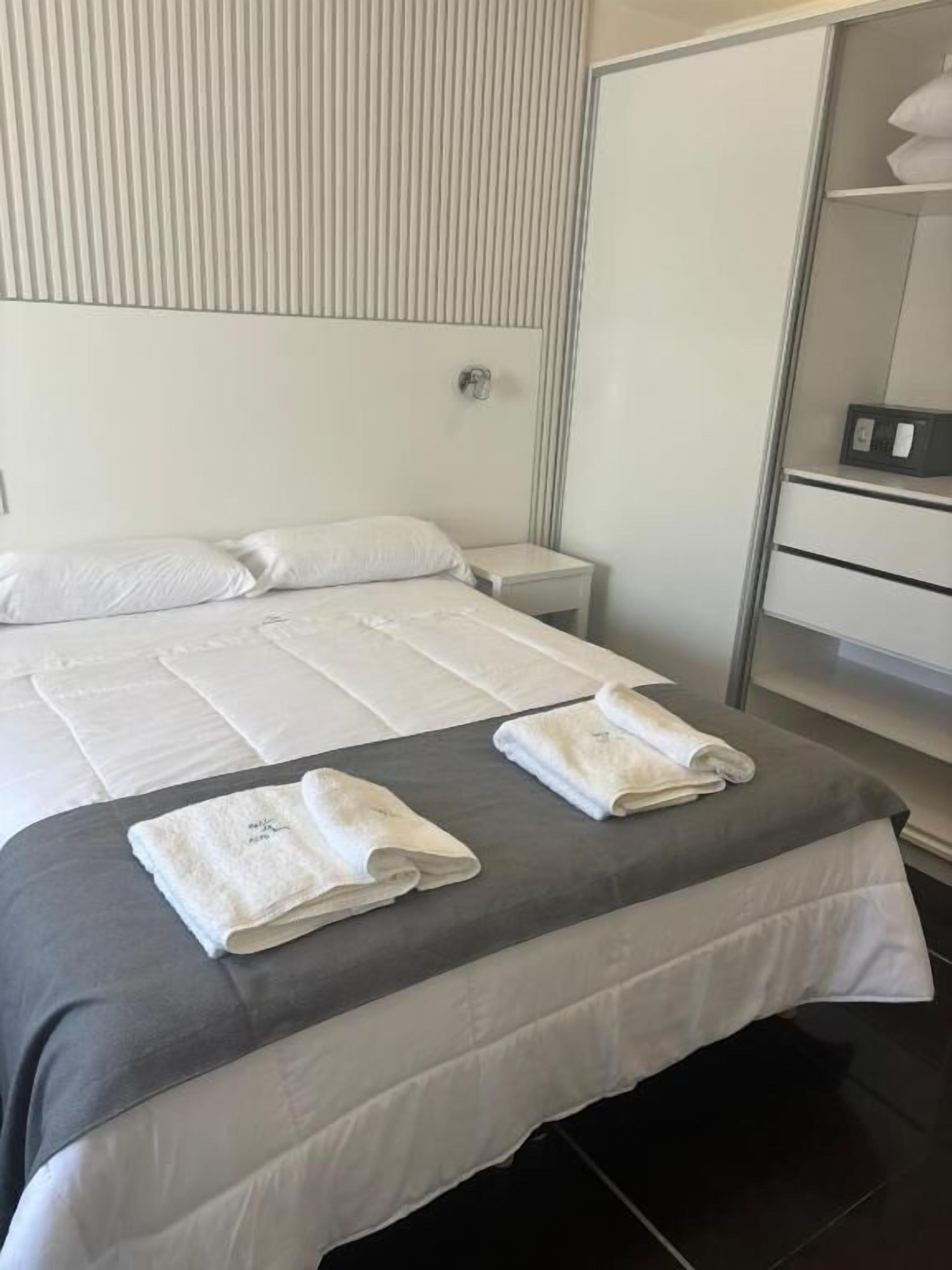 Ein Hotelzimmer mit Bett, Nachttisch, Kleiderschrank und Spiegel.