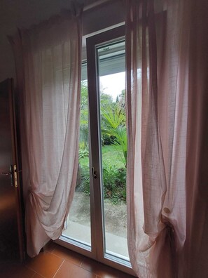 A room with a sliding glass door leading to a garden. - La Barchessa: A Plunge into Nature (Riva del Garda)