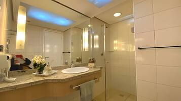 Un baño moderno con un espejo grande, un lavamanos y una cabina de ducha de vidrio.