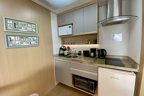 A compact kitchen with a built-in microwave, a coffee maker, and a dishwasher. - SHB Brilho do Mar Vista para o Oceano (Santos)