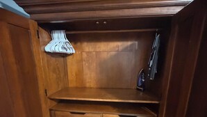 A wooden cabinet with multiple drawers and a hanging rack. - The Blue Palace (Tampa)