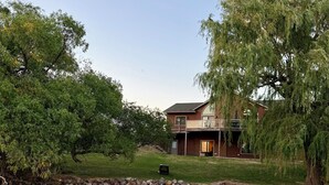 A wooden dock extending into a river, a stone wall, and a house with a balcony.