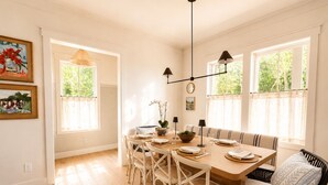 A dining area with a wooden table, white chairs, and a bench. There are two pendant lights above the table. - Rabbit Ridge New Designer Cottage Screened Porch + Wood Fireplace | EV Charger (Cashiers)