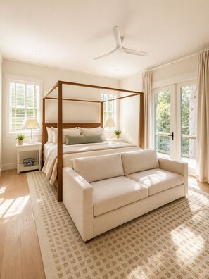 Ein Schlafzimmer mit einem Himmelbett, einer Couch, einem Deckenventilator und großen Fenstern.