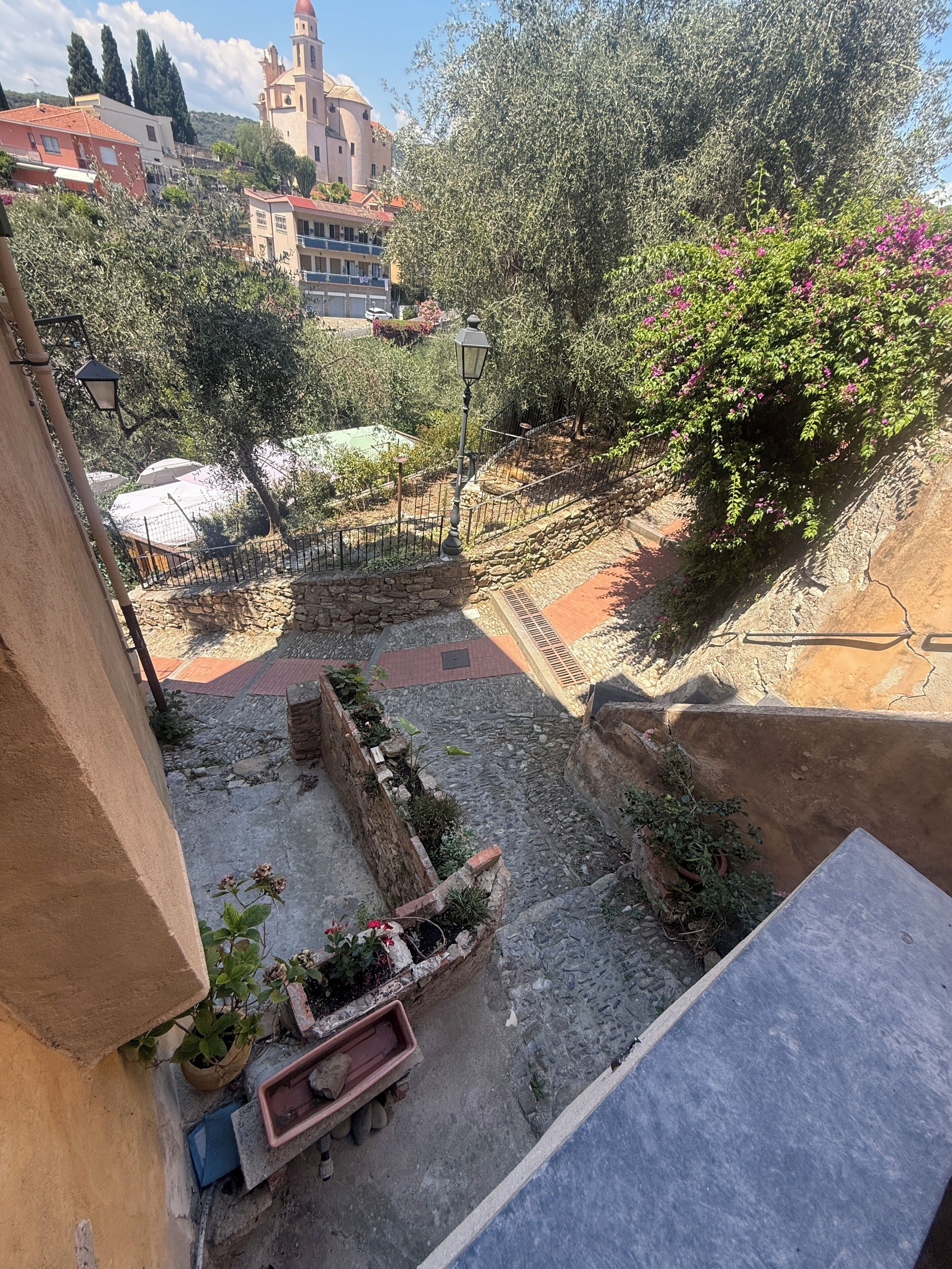 A courtyard with stone walls, a fountain, and a view of a historic building in the background.