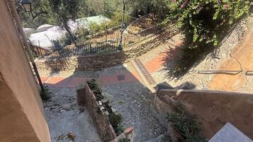 A courtyard with stone walls, a fountain, and a view of a historic building in the background.