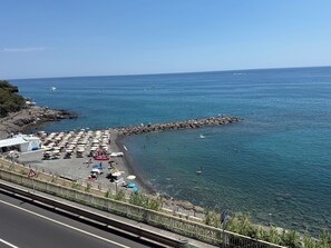 A coastal beach with umbrellas, a rocky breakwater, and a clear view of the sea. - Terrazza Palazzo Viale Cervo (Cervo)