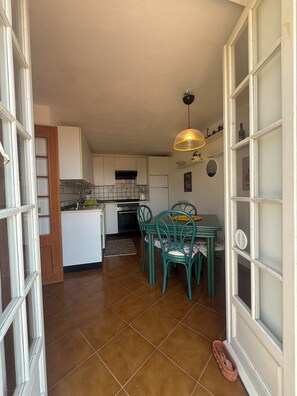 A kitchen with white cabinets, a dining table with chairs, and a hanging light fixture. - Terrazza Palazzo Viale Cervo (Cervo)