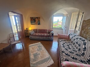 A cozy living room with a sofa, a chair, a rug, and a painting on the wall. - TERRAZZA PALAZZO VIALE CERVO (Cervo)