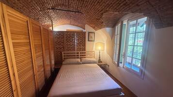 A room with a bed, a window, and a wooden ceiling.
