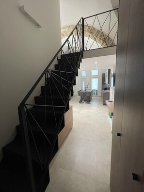 Ein modernes Interieur mit einer schwarzen Metalltreppe, die in einen Wohnbereich führt.