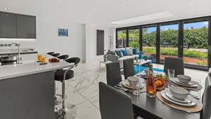 A modern kitchen with a dining area, a large window, and a view of a swimming pool.