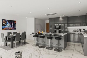 Eine moderne Küche mit einer zentralen Kochinsel, Barhocker und einem Essbereich mit Tisch und Stühlen.