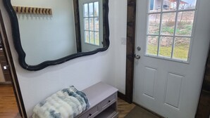 Ein Zimmer mit einer Sitzbank, einem Spiegel, einer Tür und Blick ins Freie.