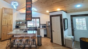 A modern kitchen with wooden cabinets, a marble island with stools, and a hanging light fixture.