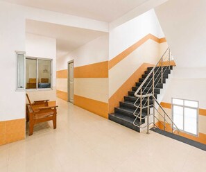 Eine Hotelhalle mit Treppe, einer Bank und einer Tür.