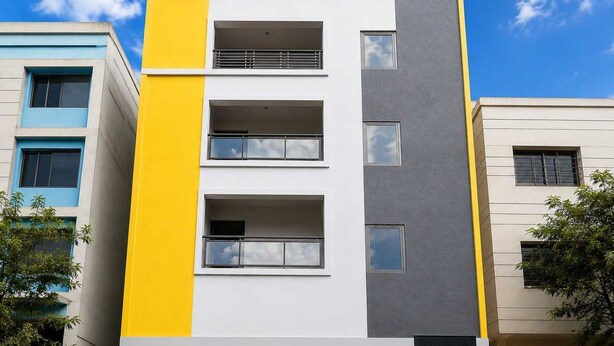 En flervåningsbostadsbyggnad med en slät fasad, balkonger och en överbyggd entré.