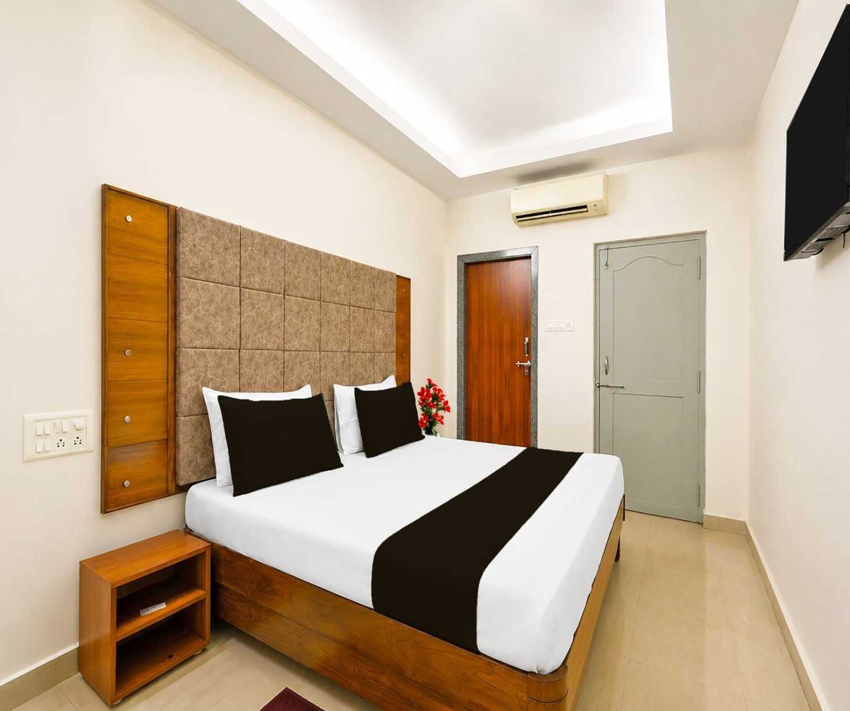 A hotel room with a bed, bedside table, wardrobe, and a television.