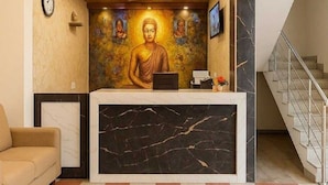 Ett entrérum med en Buddha-staty, en klocka, en takfläkt och en trappa.