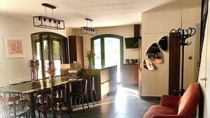 A spacious living area with a dining table, chairs, a red armchair, and a kitchen with a large window. - Villa de La Verdière, perfect for families (La Verdière)