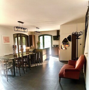 A spacious living area with a dining table, chairs, a red armchair, and a kitchen with a large window. - Villa de La Verdière, perfect for families (La Verdière)