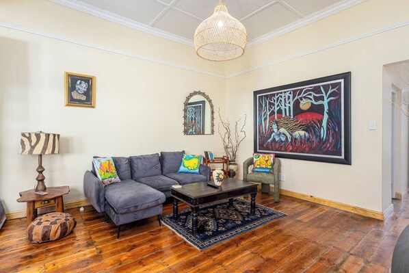 A living room with a gray sofa, a coffee table, a rug, a lamp, and a large abstract painting on the wall.