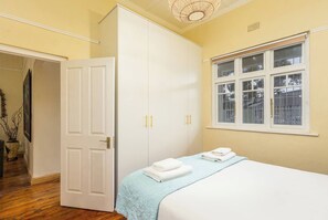 Un dormitorio con cama, armario, ventana y puerta.