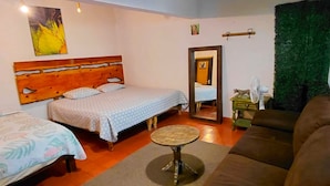 A room with a wooden ceiling, a bed with a patterned bedspread, a brown sofa, a small round table, and a green wall decoration. - Casa Aldama 83. (San Miguel de Allende)
