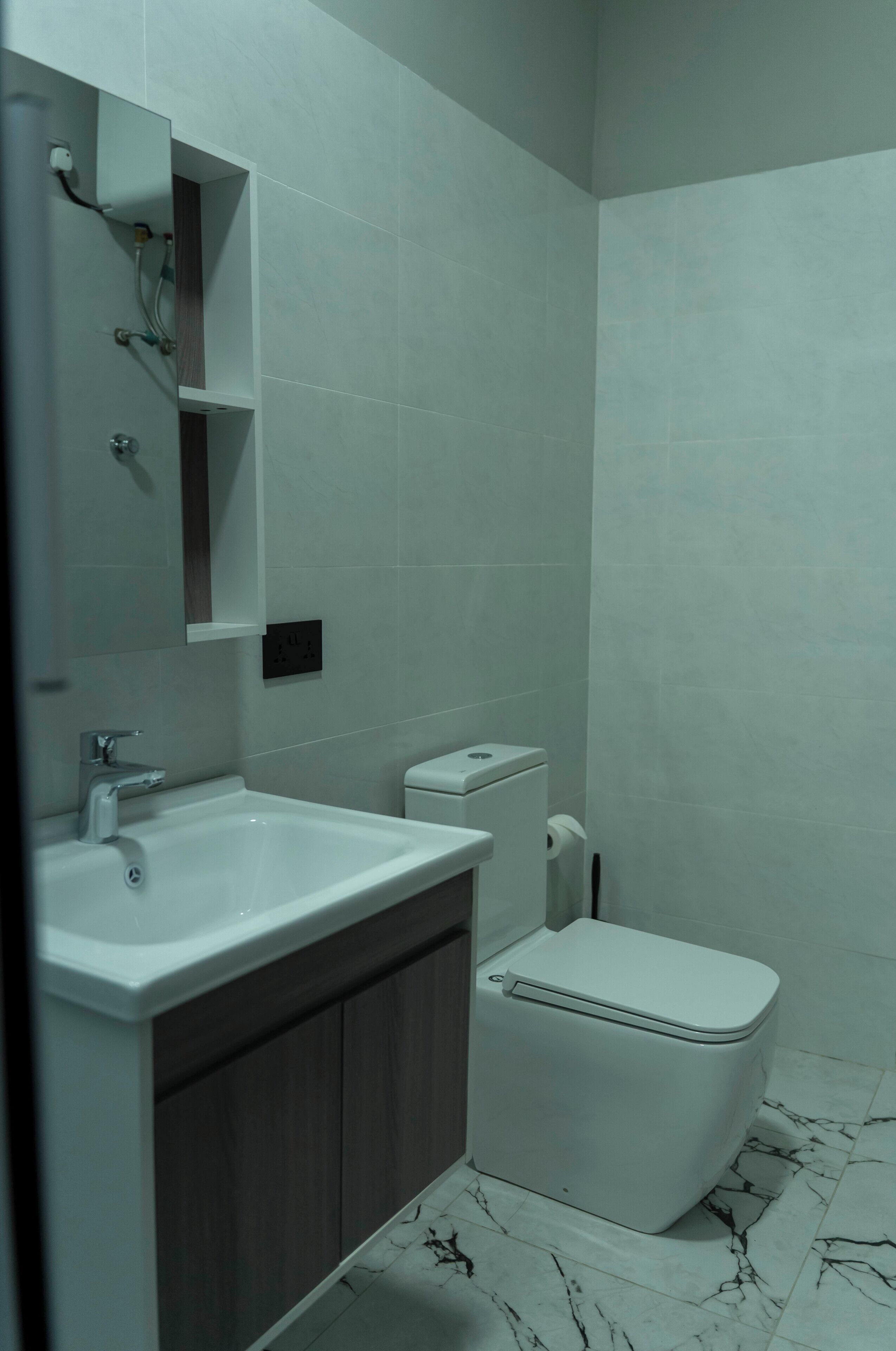Ein Badezimmer mit einem weißen Waschbecken, einer Toilette und einem Spiegel.
