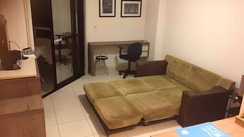 A compact living space with a sofa, a desk, and a chair.