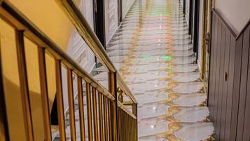 Ein Korridor mit Marmorboden, einer Treppe mit goldener Geländer und Türen auf beiden Seiten.