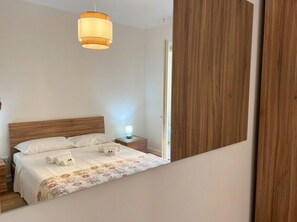 A neatly made bed with a white duvet, a bedside lamp, and rolled towels. - Tentazioni Ariose - Luxury Suite (Perugia)