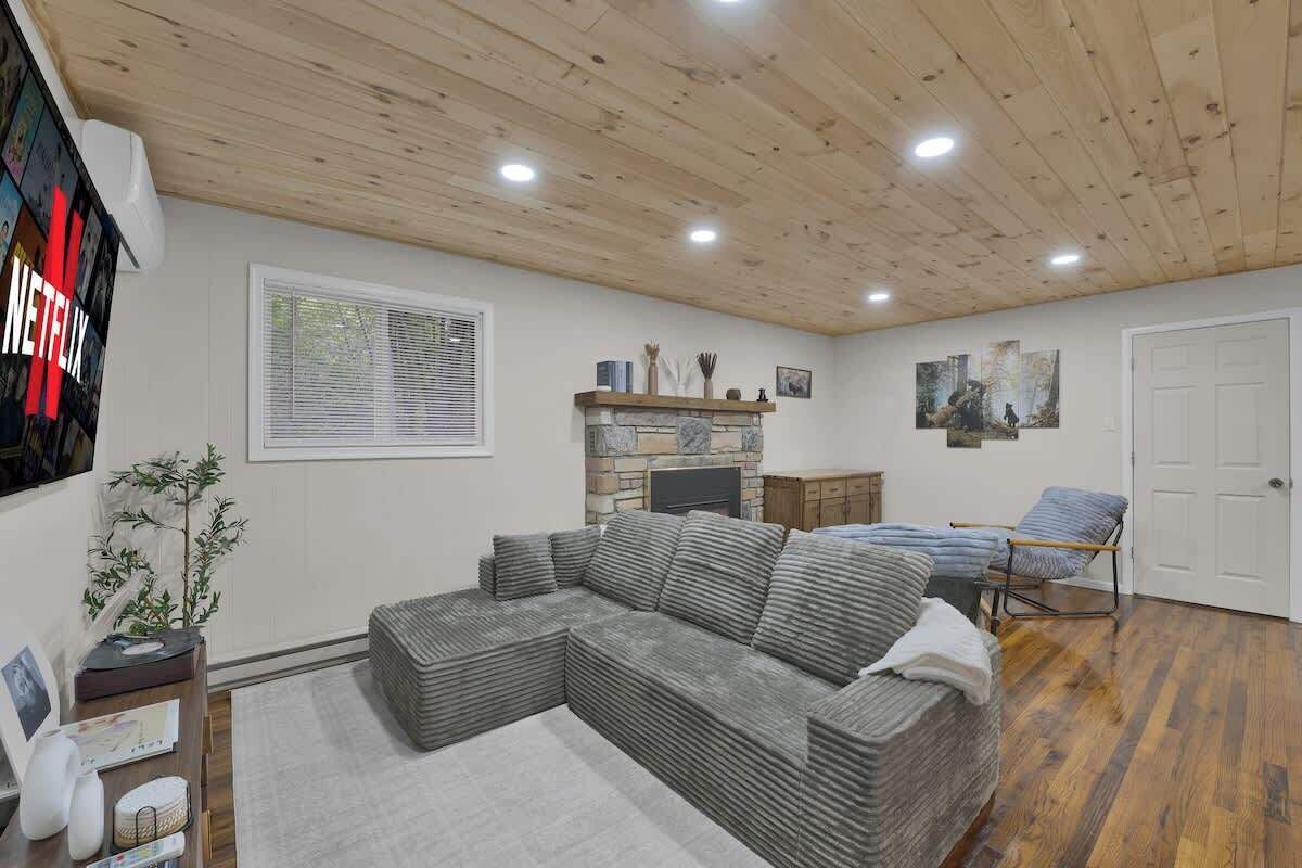 A living room with a sectional sofa, a fireplace, a TV, and a door.