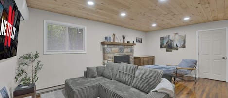 A living room with a sectional sofa, a fireplace, a TV, and a door.