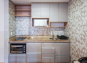 A compact kitchen with a microwave, oven, and sink. - SHB Oásis Familiar Pé na Areia (Santos)