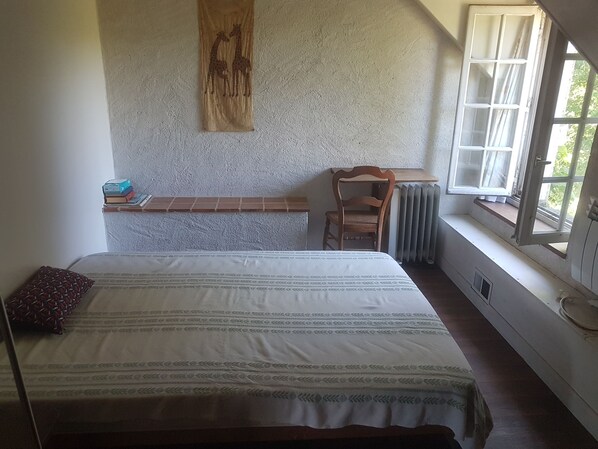 A bedroom with a bed, a chair, a radiator, a window, and a wall with a wooden carving. - Bed and Breakfast: Cycling in the Loire Valley (Poilly-lez-Gien)