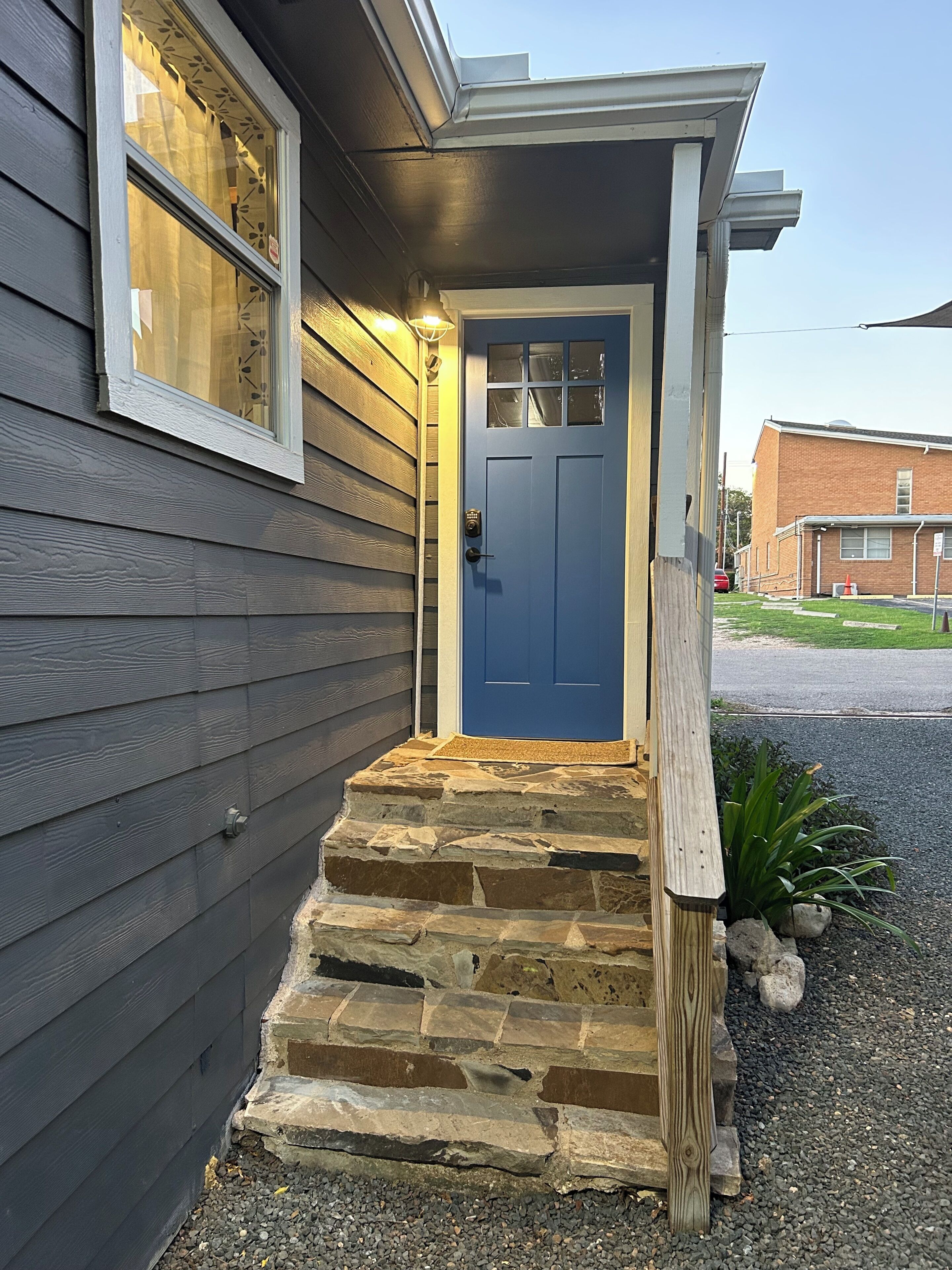 Una casa con puerta azul, escalones de piedra y un poste de madera.