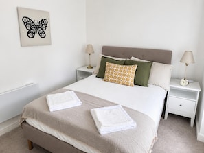 A neatly made bed with two pillows, a bedside lamp, and a wall art piece. - Stony Stratford Cozy Apartment (Milton Keynes)