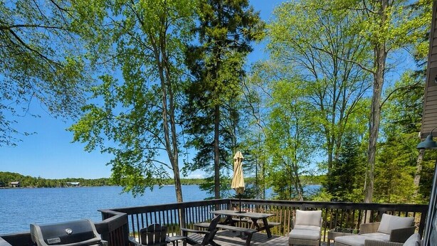 Une terrasse dotée de mobilier d’extérieur, d’un barbecue et offrant une vue sur un lac.