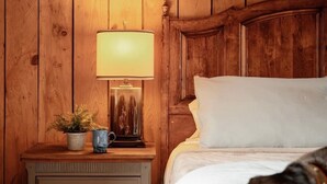 Eine Holzwand mit einem Nachttisch, einer Lampe, einer Pflanze und einem Bett, in dem ein Hund liegt.