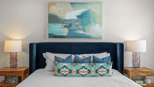 A bedroom with a large bed, two bedside tables, a nightstand, a decorative pillow, and a painting on the wall. - Bayside Getaway - Near Beach (Orange Beach)