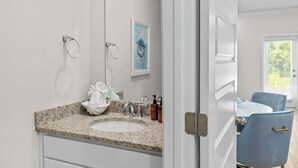 A bathroom with a granite countertop sink, a towel, and a framed artwork on the wall. - Bayside Getaway - Near Beach (Orange Beach)
