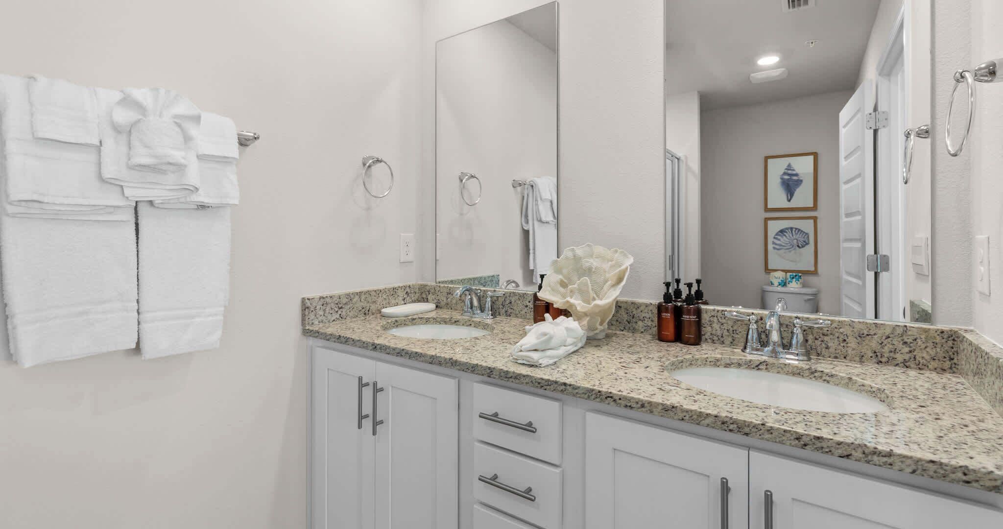 A bathroom with two sinks, a large mirror, and a towel rack with folded towels.