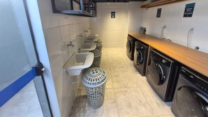 Des toilettes publiques équipées de lavabos, d’une poubelle et d’un espace buanderie avec des machines à laver.