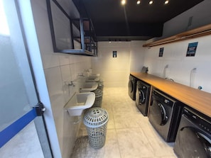 Des toilettes publiques équipées de lavabos, d’une poubelle et d’un espace buanderie avec des machines à laver.